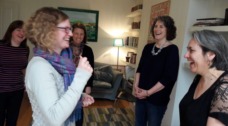 A group of woman facing each other and laughing together during a creative play workshop for adults